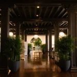 Interior lobby of hotel, dark wood and plants with front desk and seating area