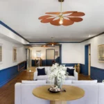Beach hotel lobby with blue molding and orange overhead flower lamp, white sofas