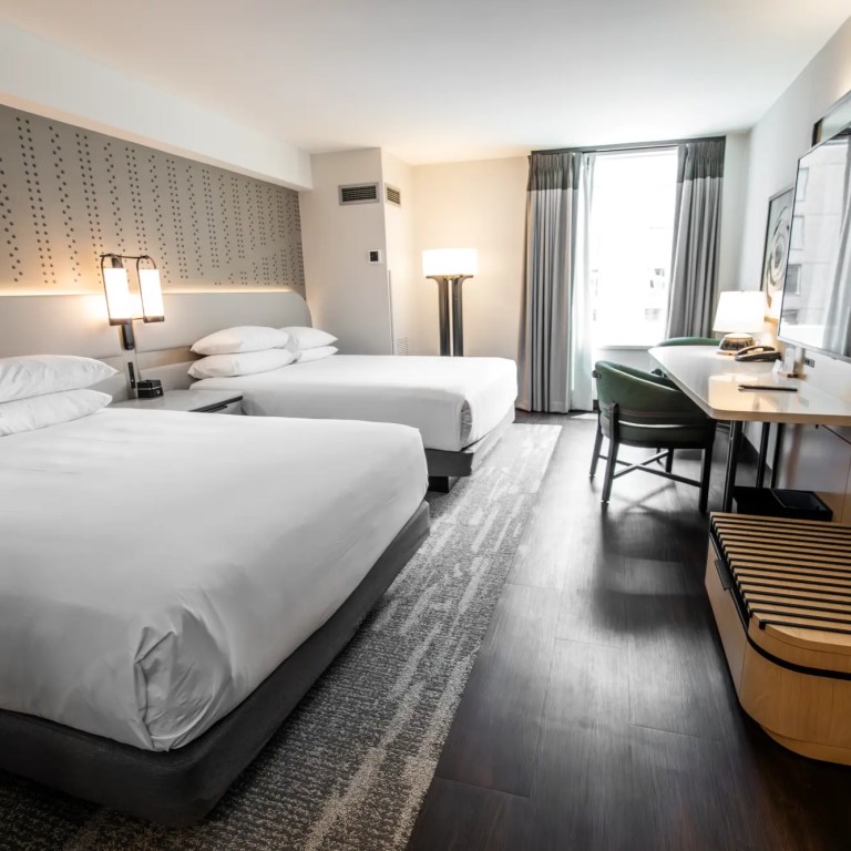Hotel guest room with two queen beds and desk with chair