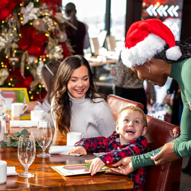 mother and son at festive Christmas brunch with server in Santa hat